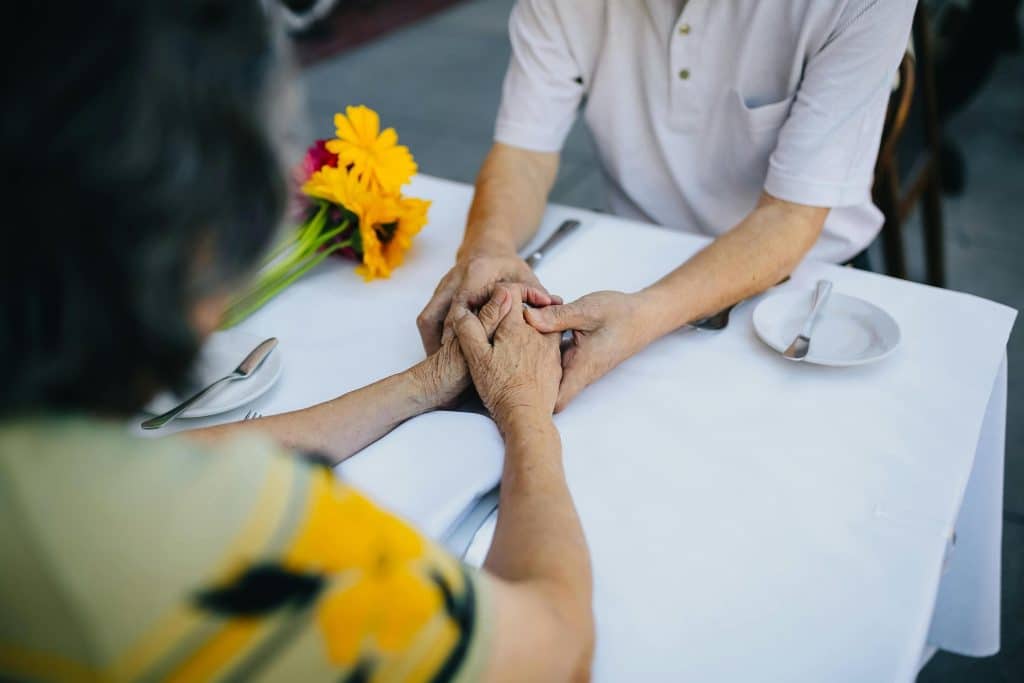 two people holding hands over a table